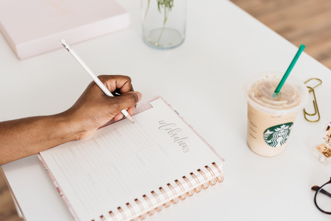 person writing in planner with coffee on desk morning
