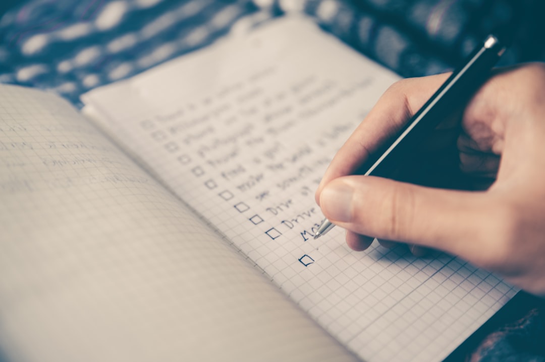 person checking off habit tracker checklist notebook