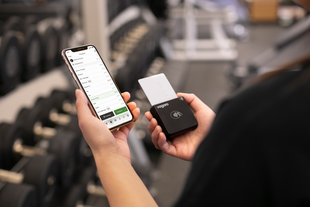 man checking workout app on smartphone at gym between sets