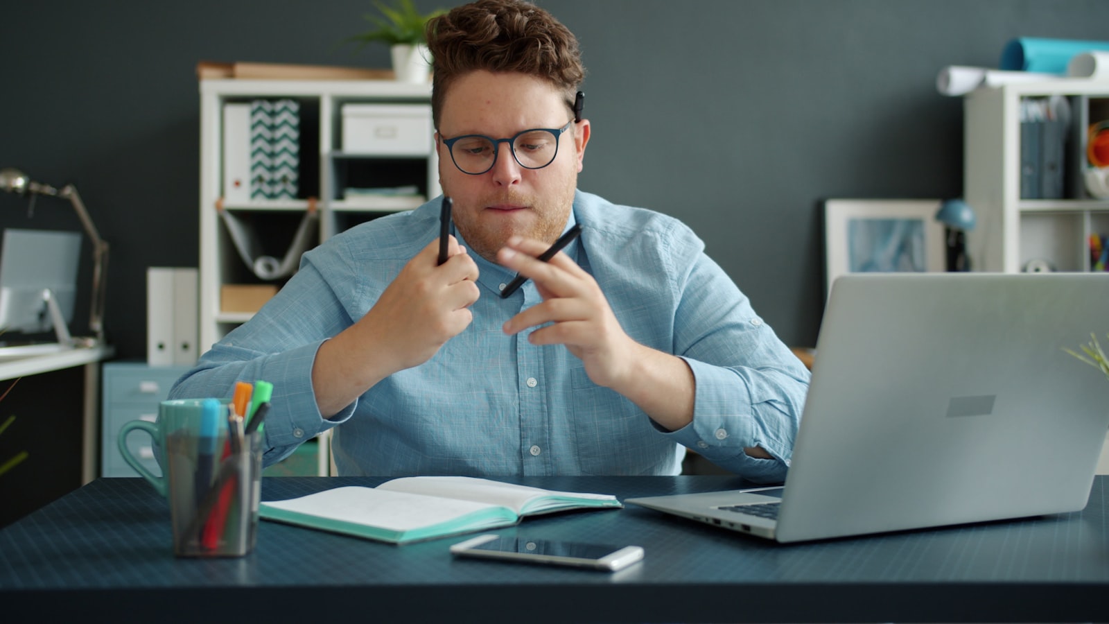 Homem pensando diante de um caderno na mesa de trabalho