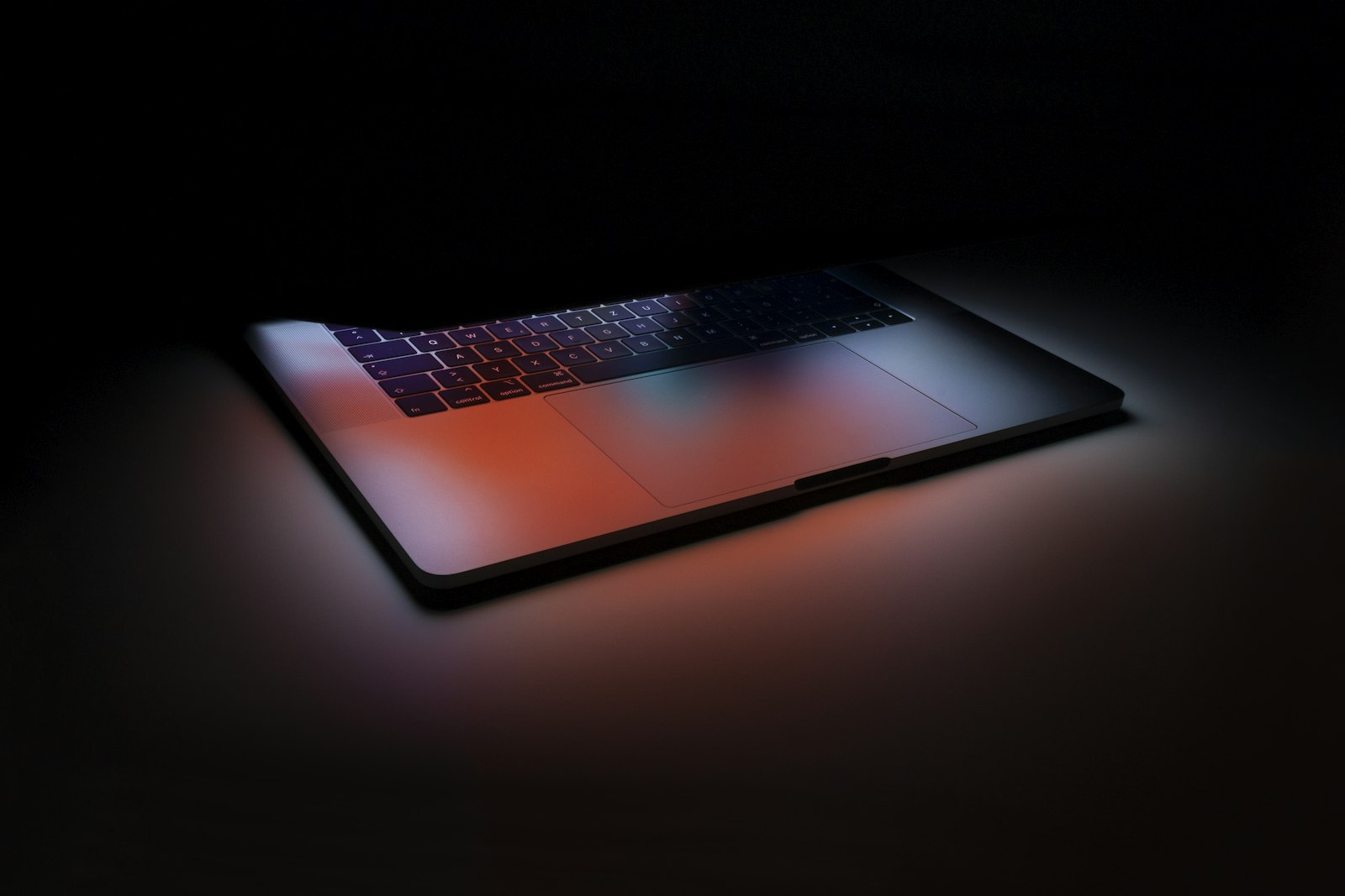 Notebook aberto e ligado sobre a mesa em um quarto escuro