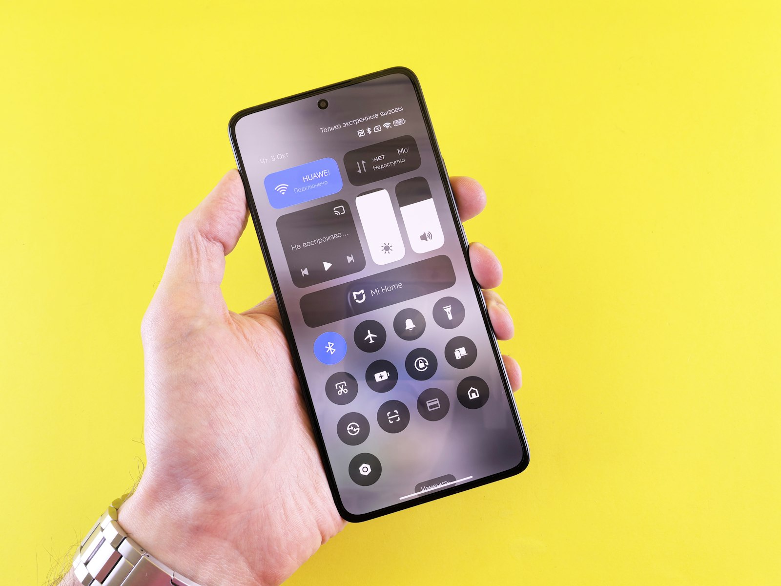 Mão segurando um smartphone com o painel de ajustes aberto na tela