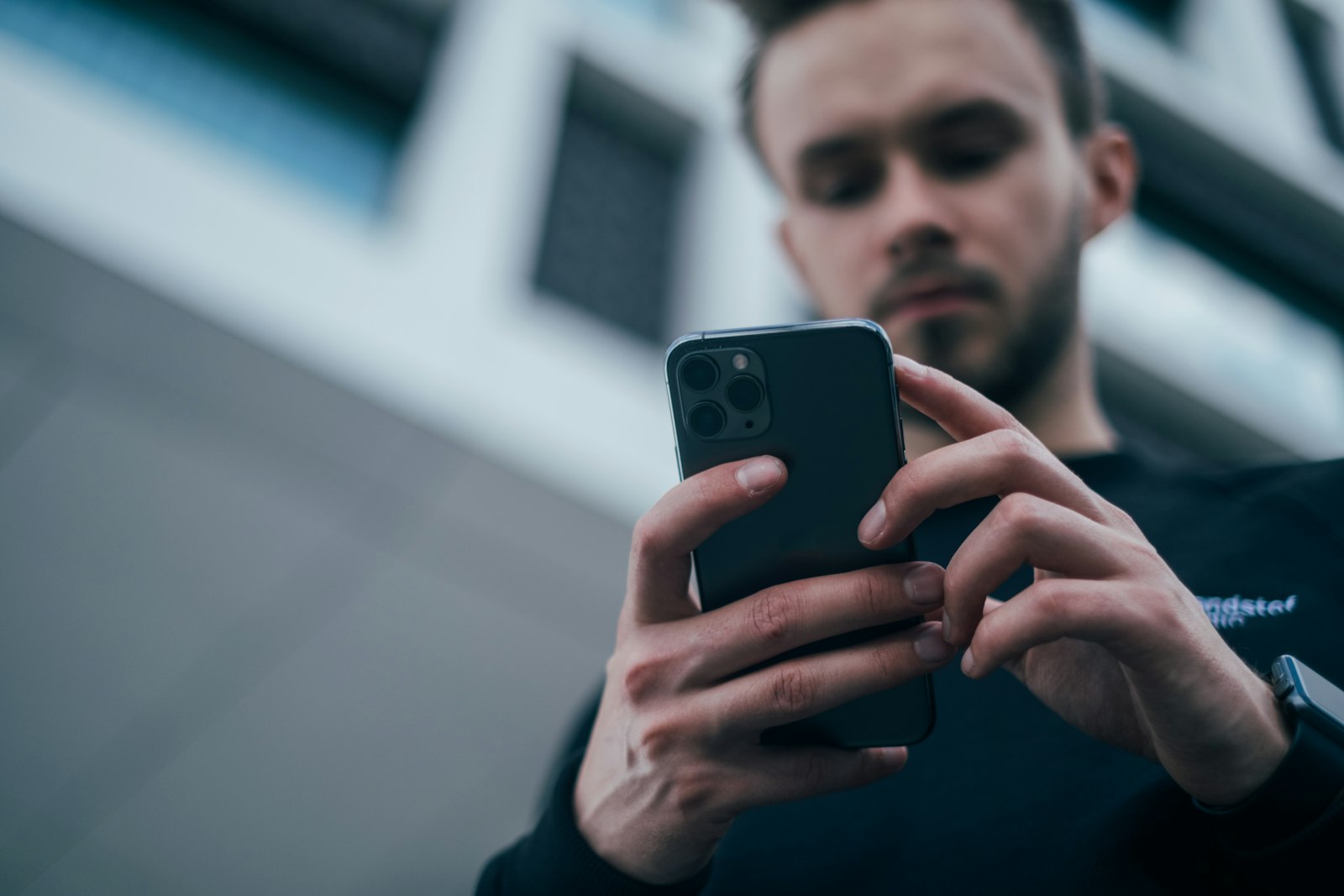 Homem de moletom escuro usando um smartphone
