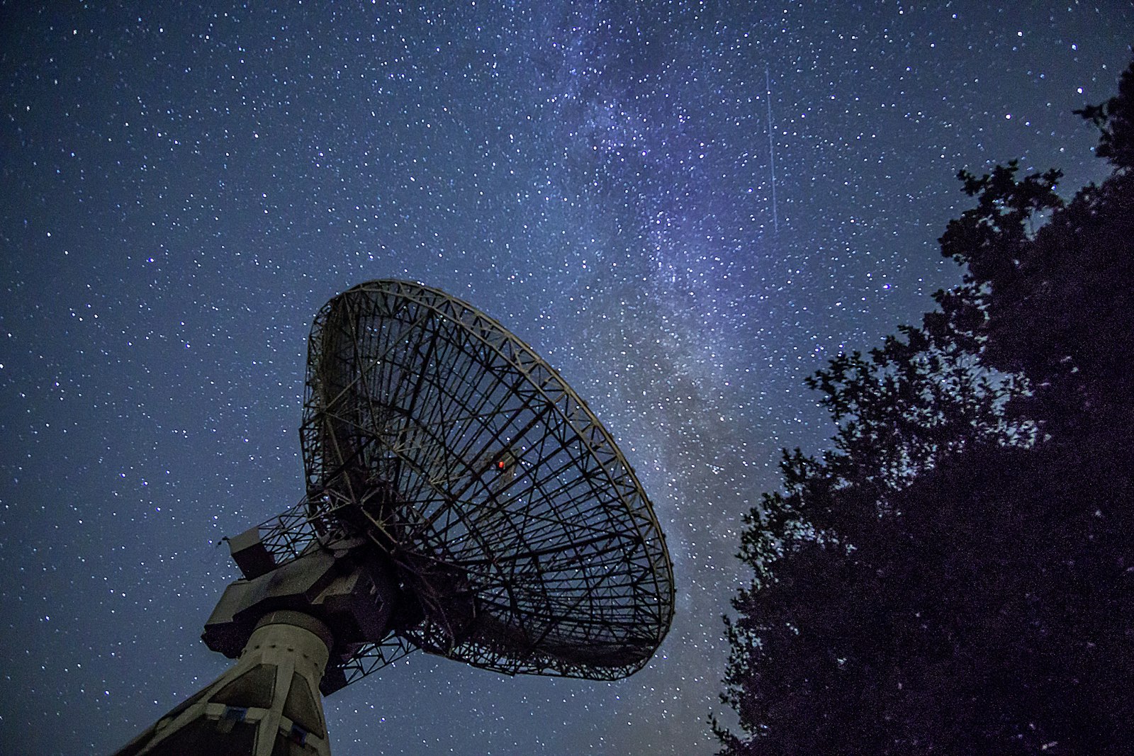 Antena parabólica apontada para o céu estrelado à noite