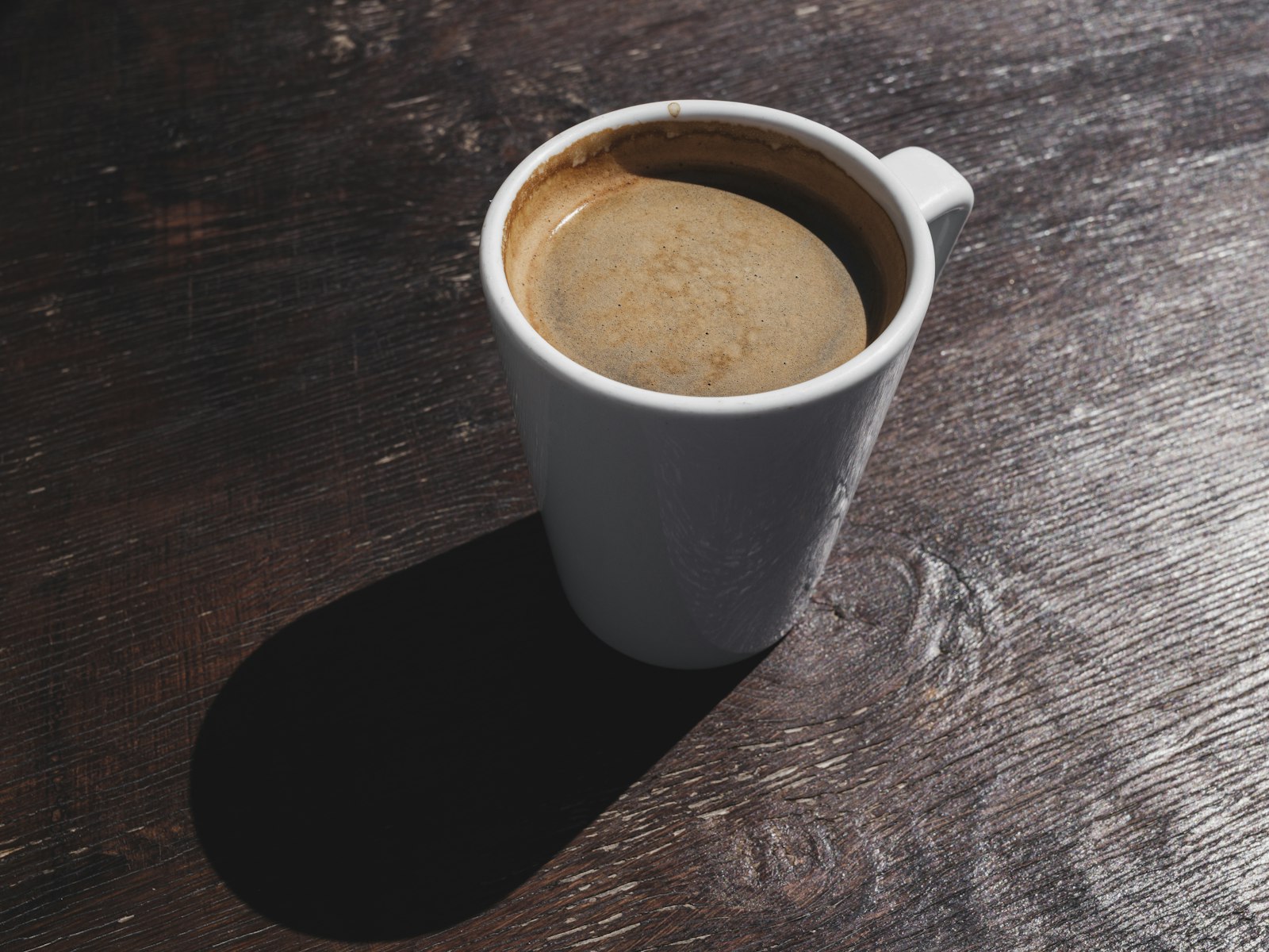 Xicara de cafe americano sobre mesa de madeira