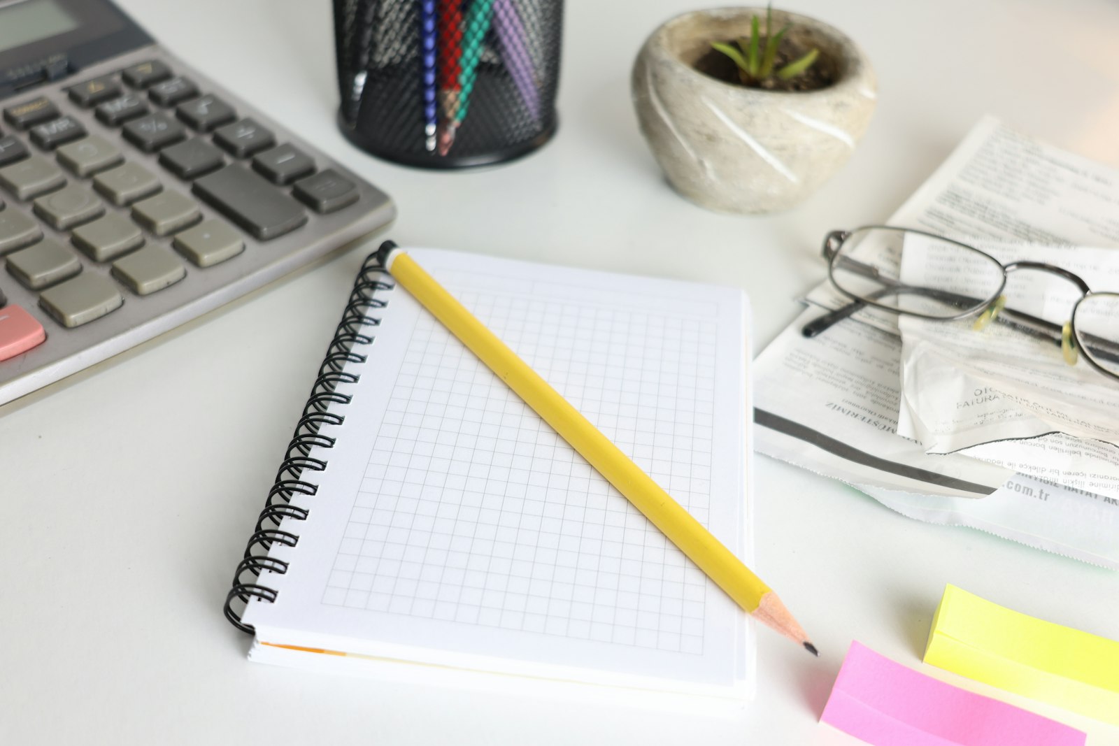 Calculadora, caderno e lapis sobre uma mesa de trabalho