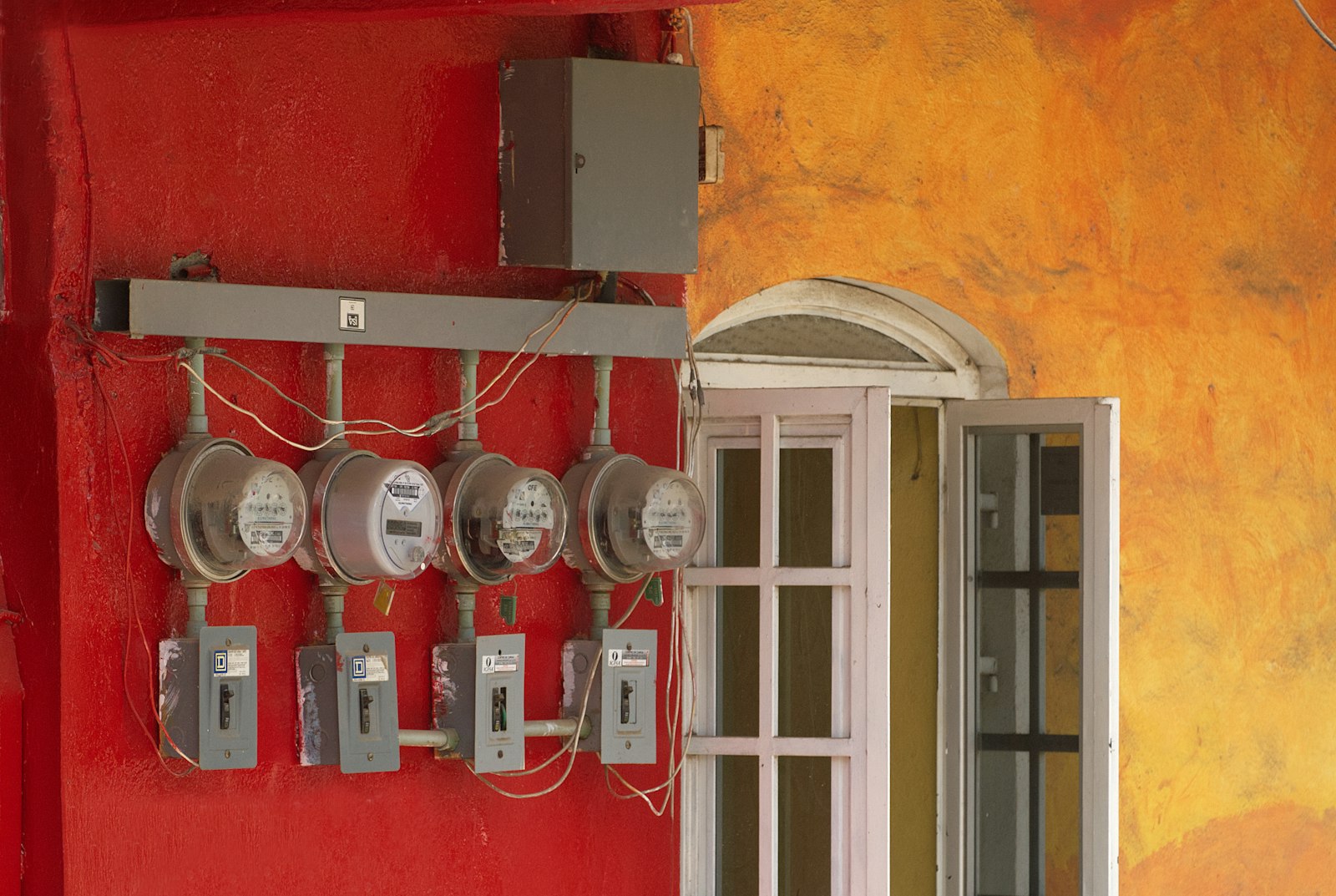 Quatro medidores de energia eletrica instalados em uma parede vermelha