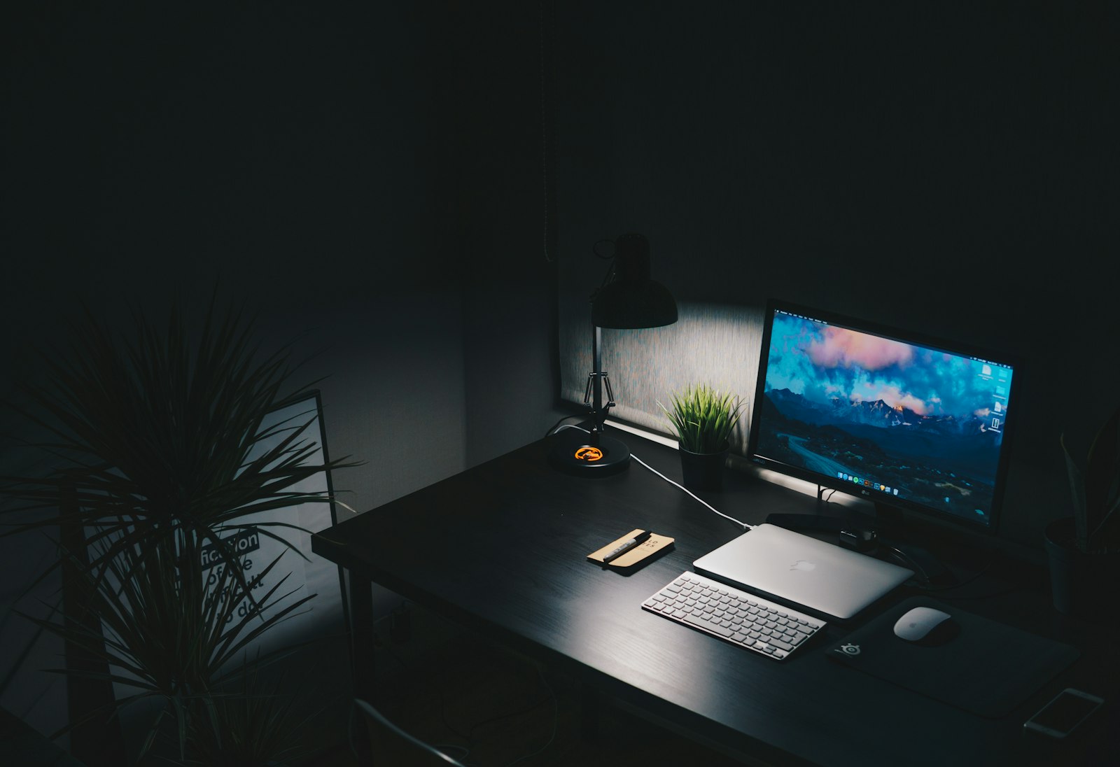 Mesa de trabalho com monitor e teclado em ambiente escuro