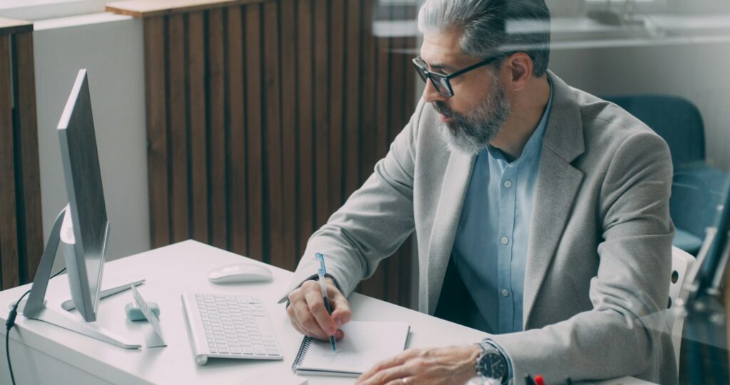 Homem sentado à mesa anotando números em um papel