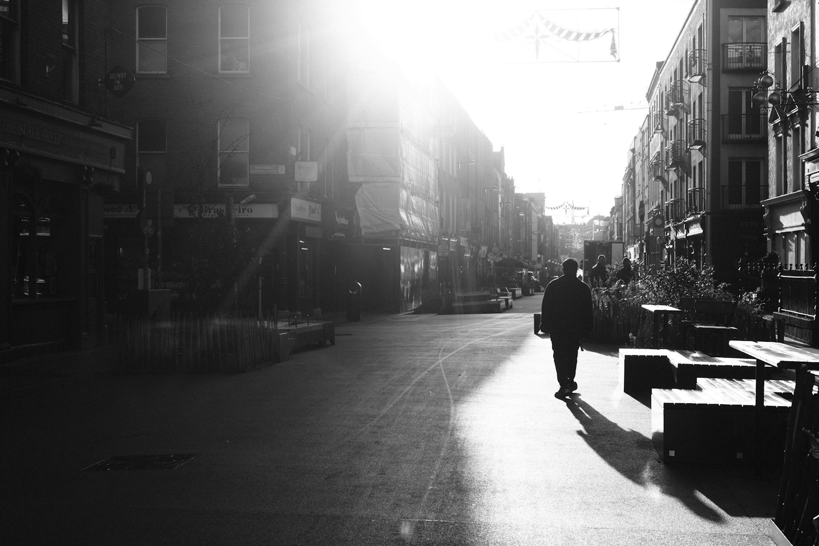 Homem caminhando por uma rua iluminada pelo sol
