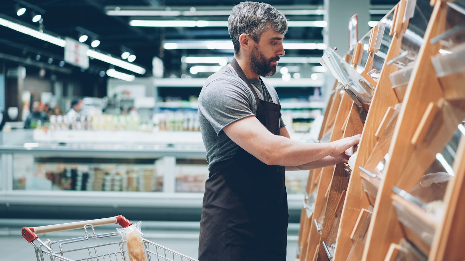 Homem organizando produtos na prateleira de um supermercado