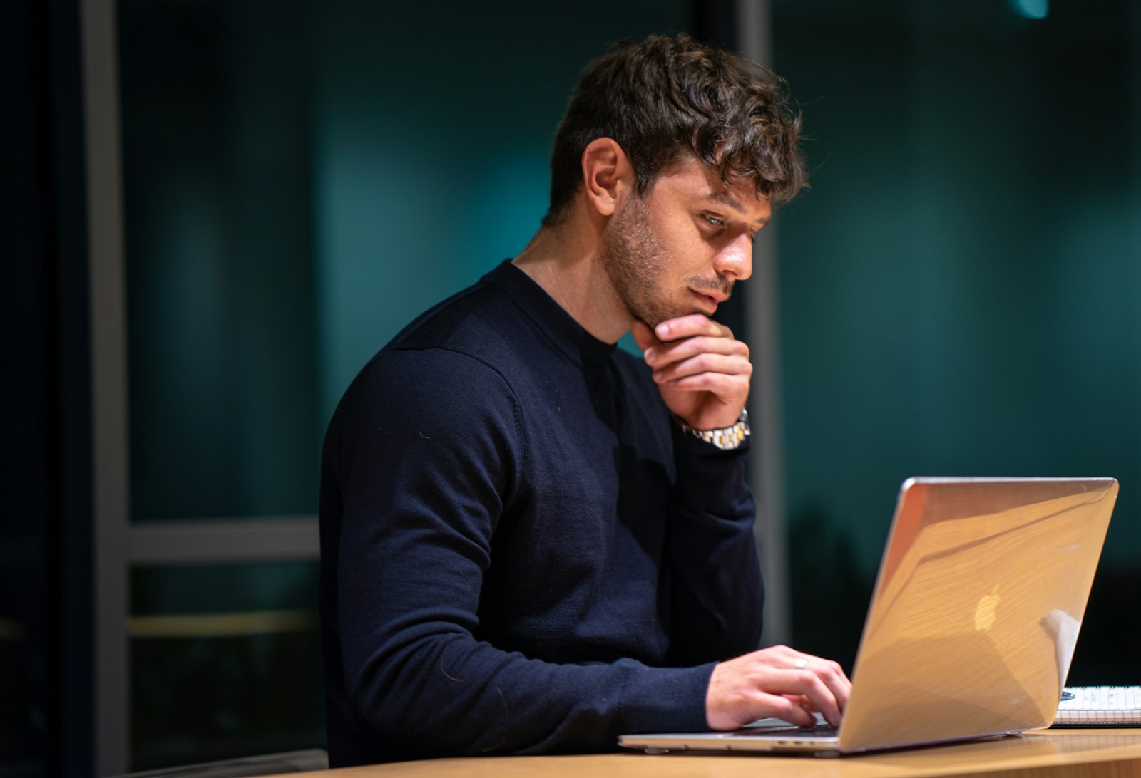 Homem sentado diante de um notebook trabalhando à noite