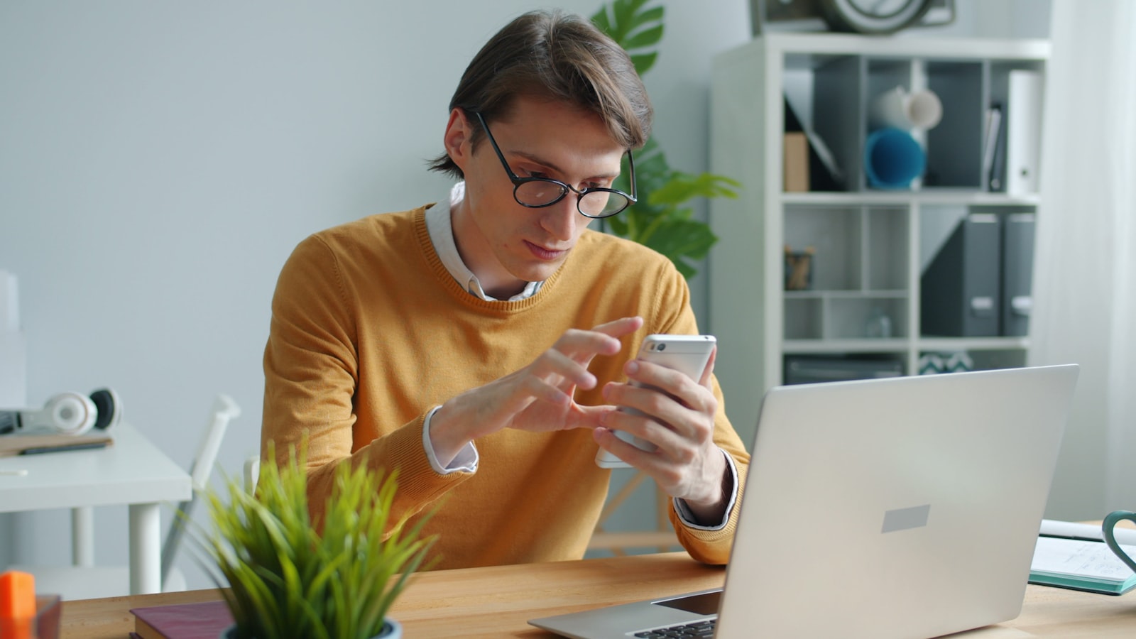 Homem conferindo informação na tela do celular sobre a mesa de trabalho