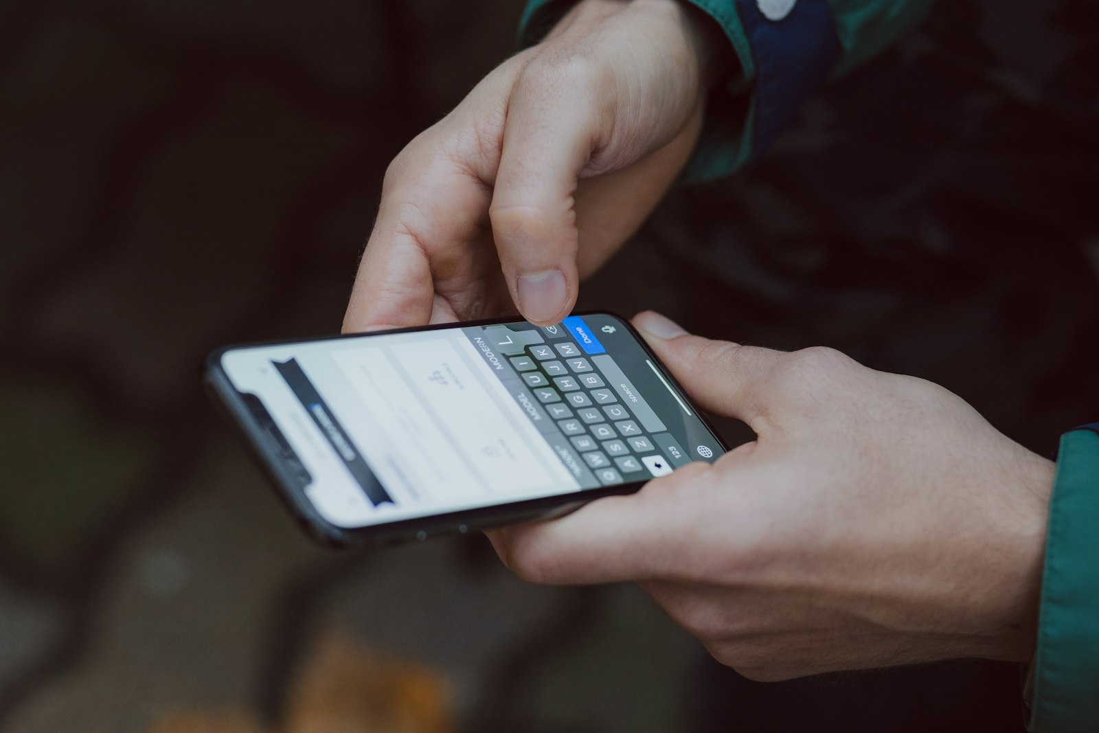 Homem de pé no escuro olhando a tela do celular durante a noite