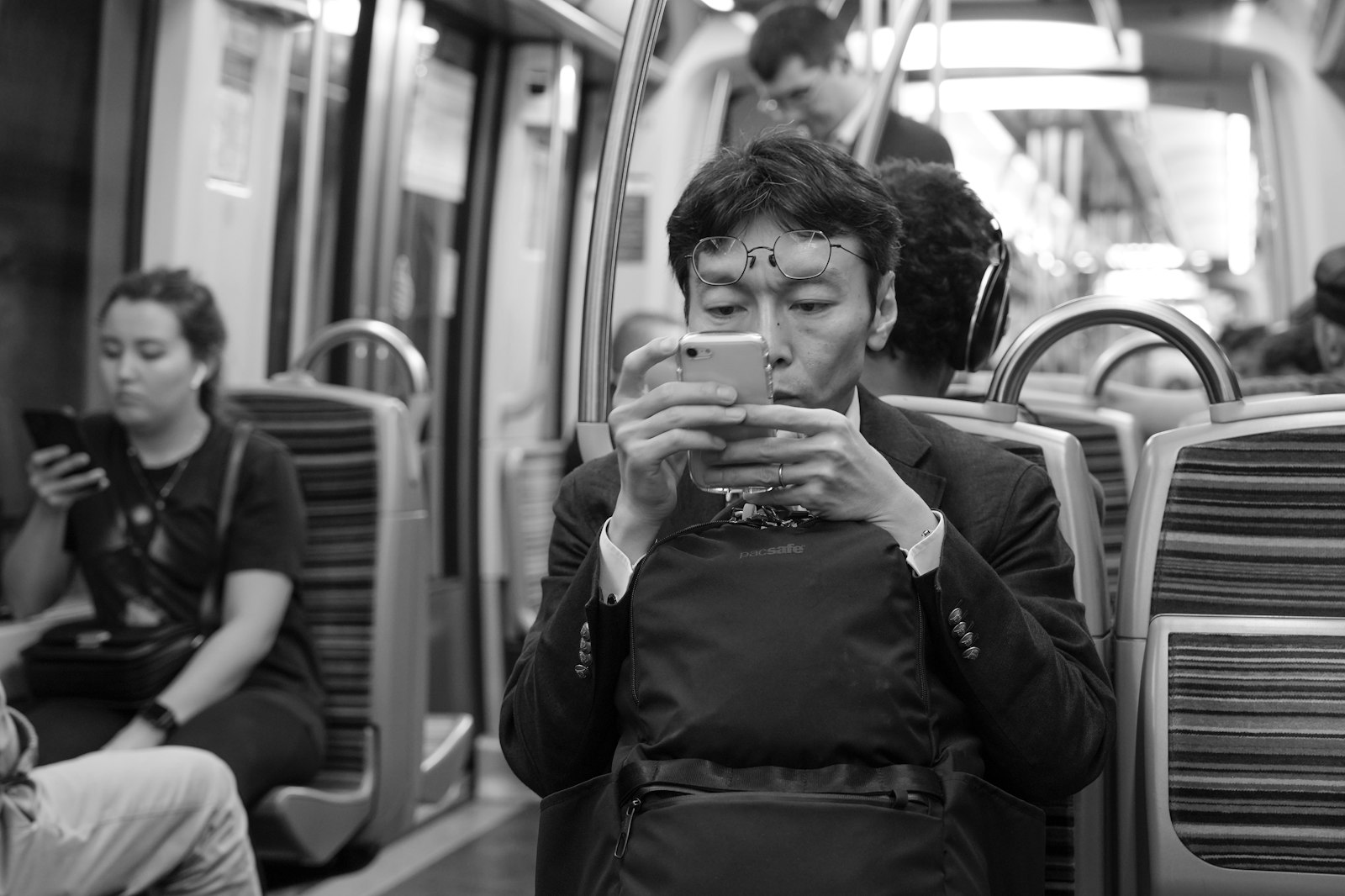 Homem usando o celular em pe dentro de um vagao de metro lotado