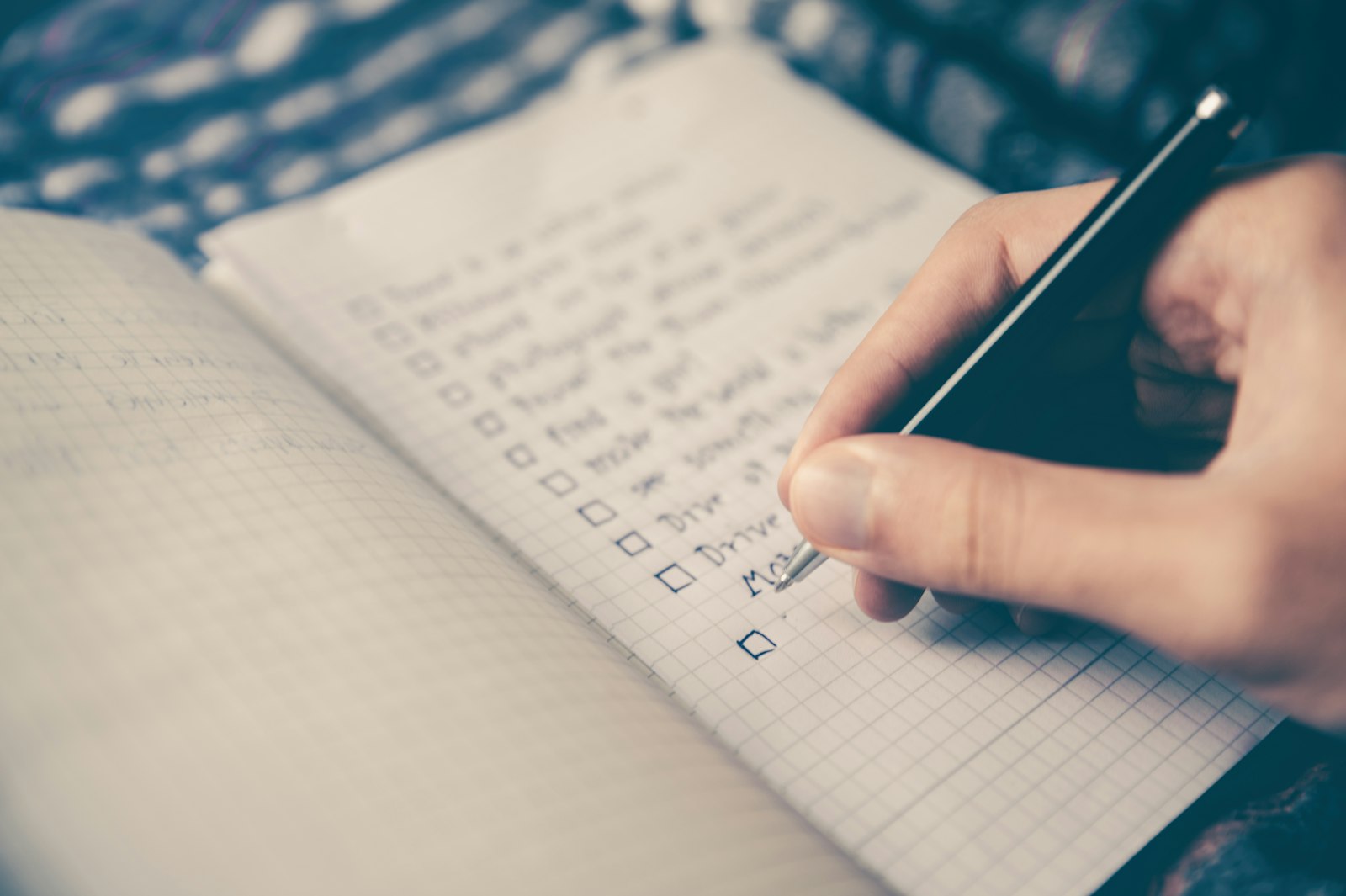 Caderno aberto em branco ao lado de um iPhone e um notebook sobre a mesa