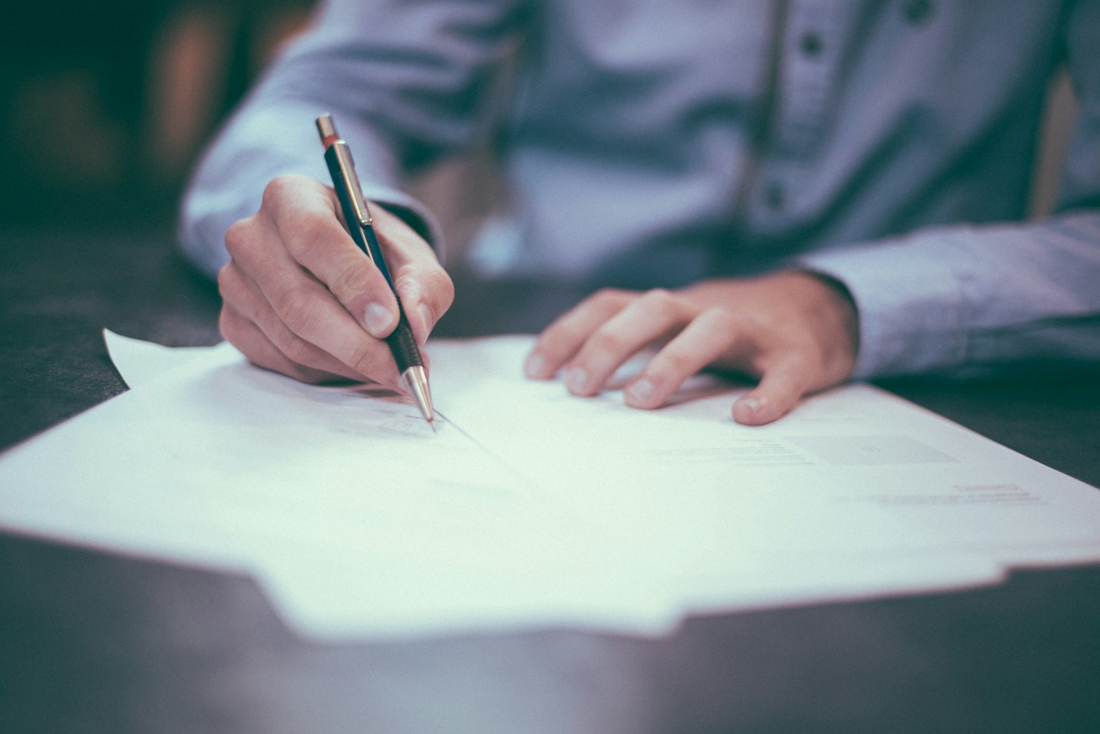 Homem fazendo contas e anotando numeros em papel sobre a mesa