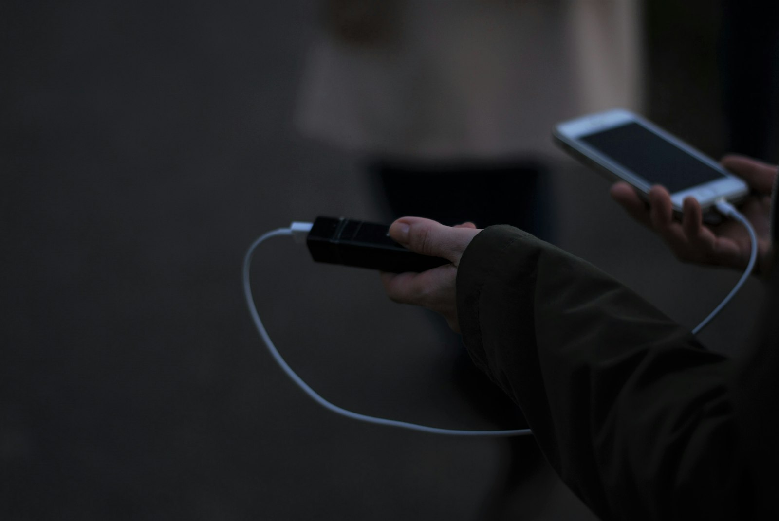 Mão segurando um power bank ligado por cabo a um celular
