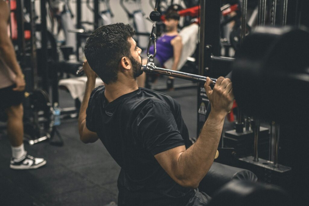 Homem fazendo puxada na frente em máquina de academia