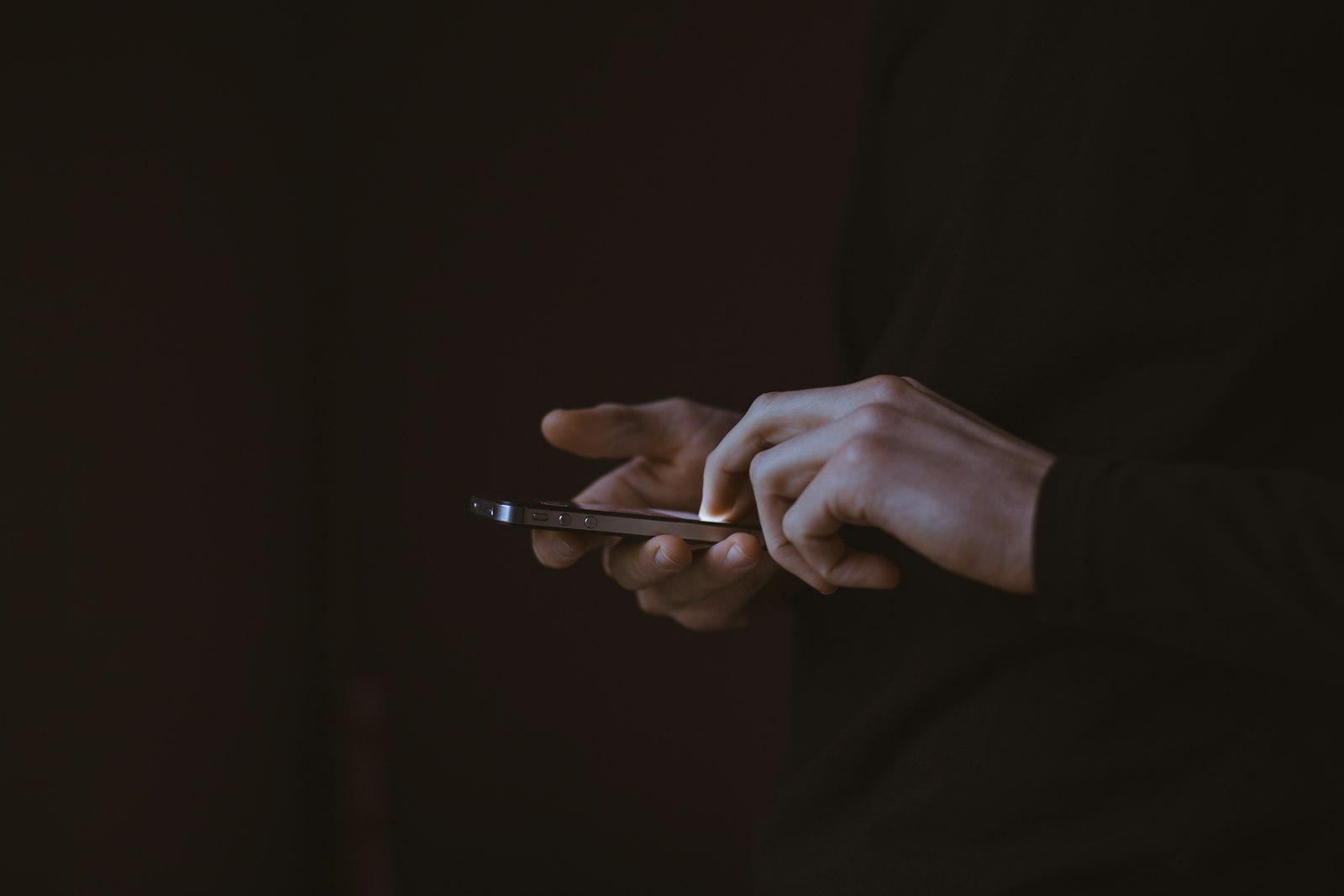 Silhueta de pessoa segurando um celular contra a luz