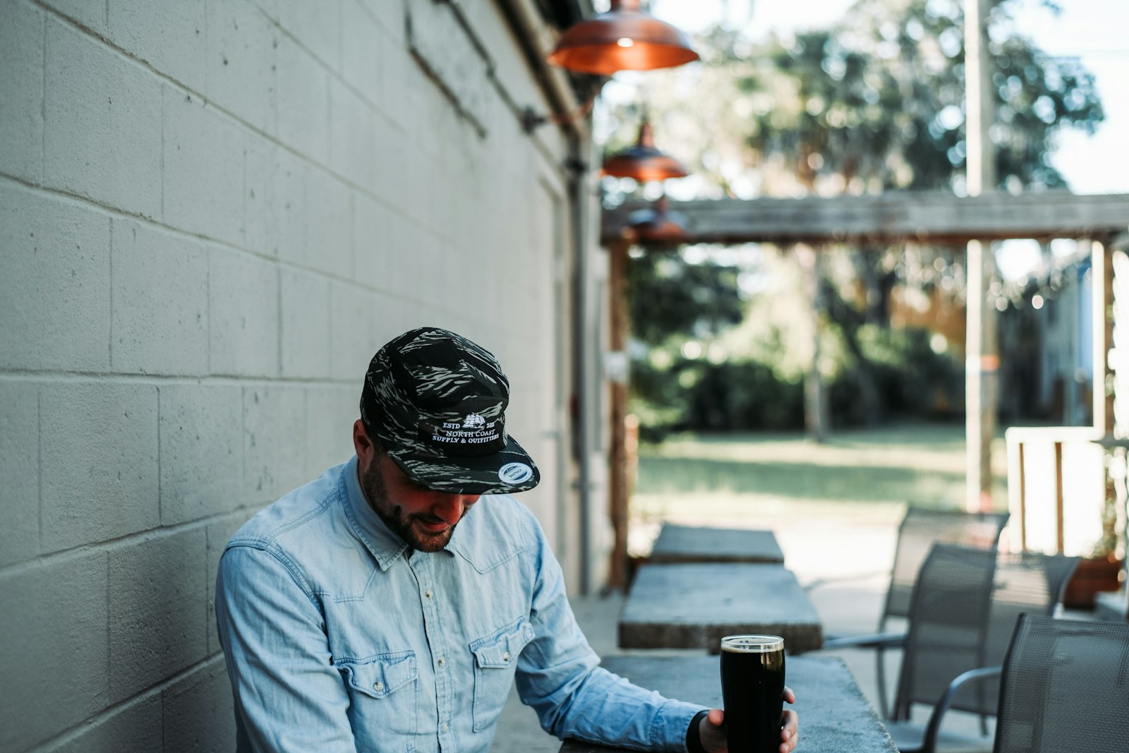 Homem sentado sozinho a uma mesa com um copo de cerveja na mão