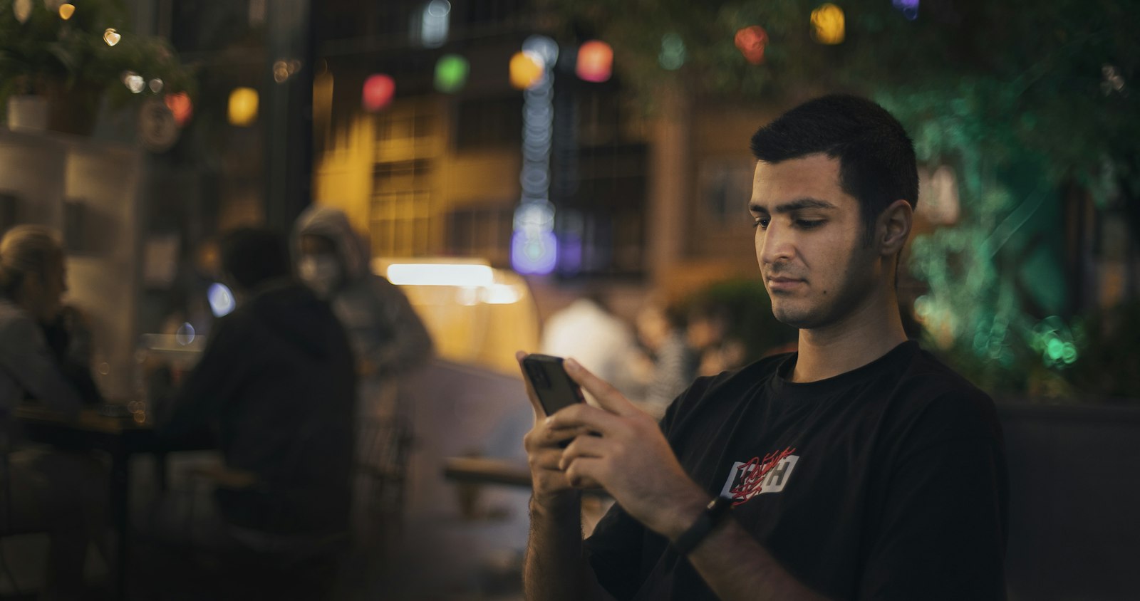 Homem parado na rua olhando a tela do celular