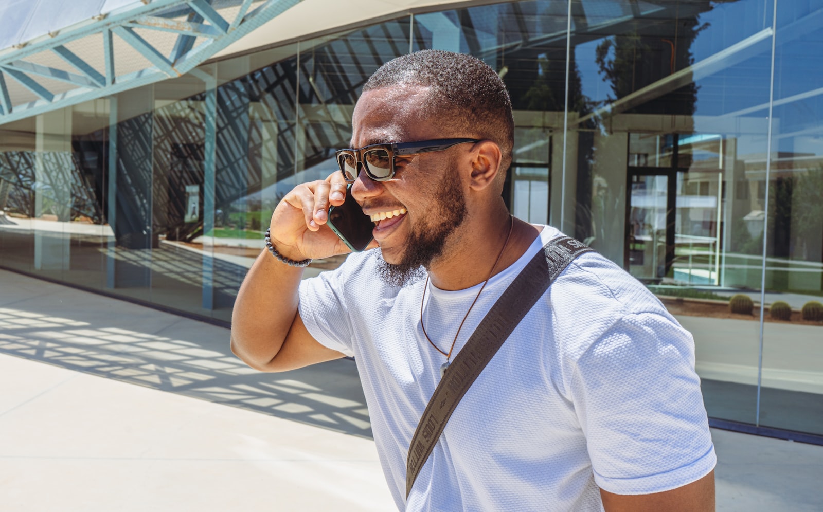 Homem de óculos escuros atendendo uma ligação no celular na rua
