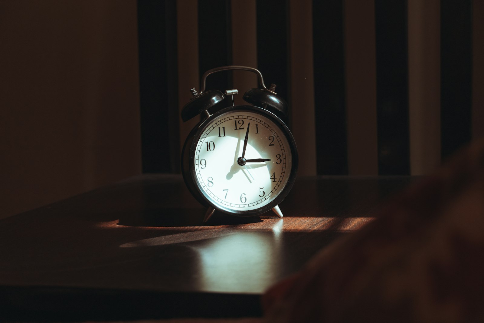 Despertador sobre uma mesa de madeira no quarto a noite