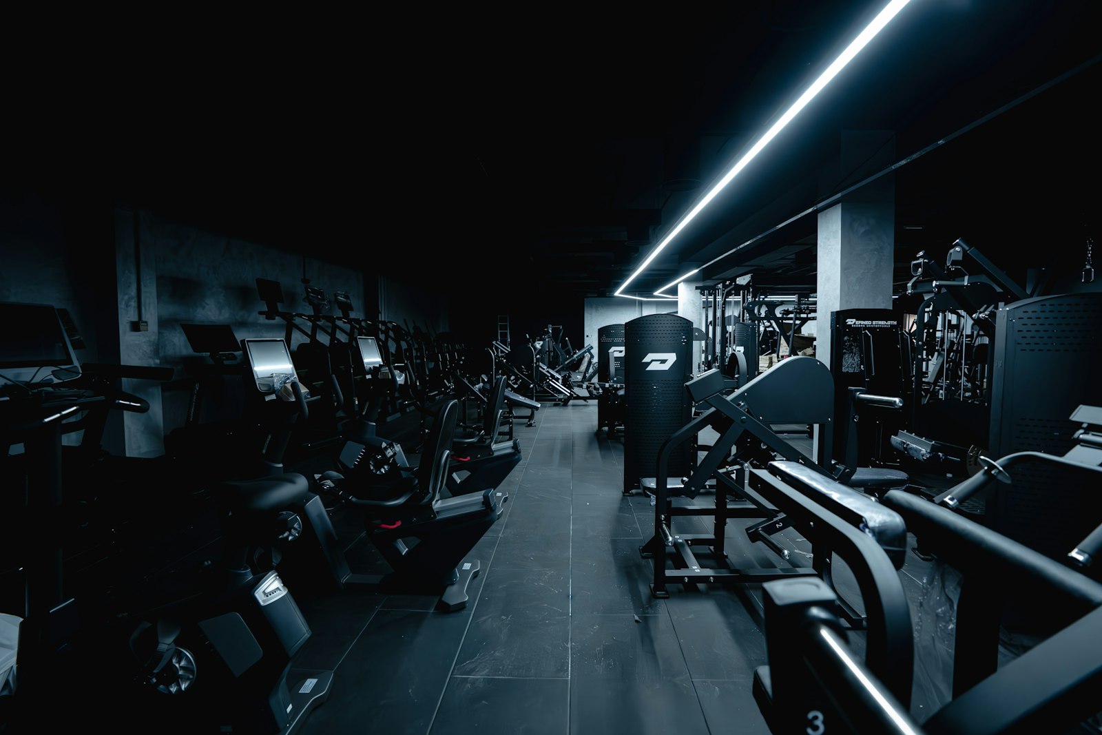 Interior de academia com pouca luz e aparelhos de musculacao