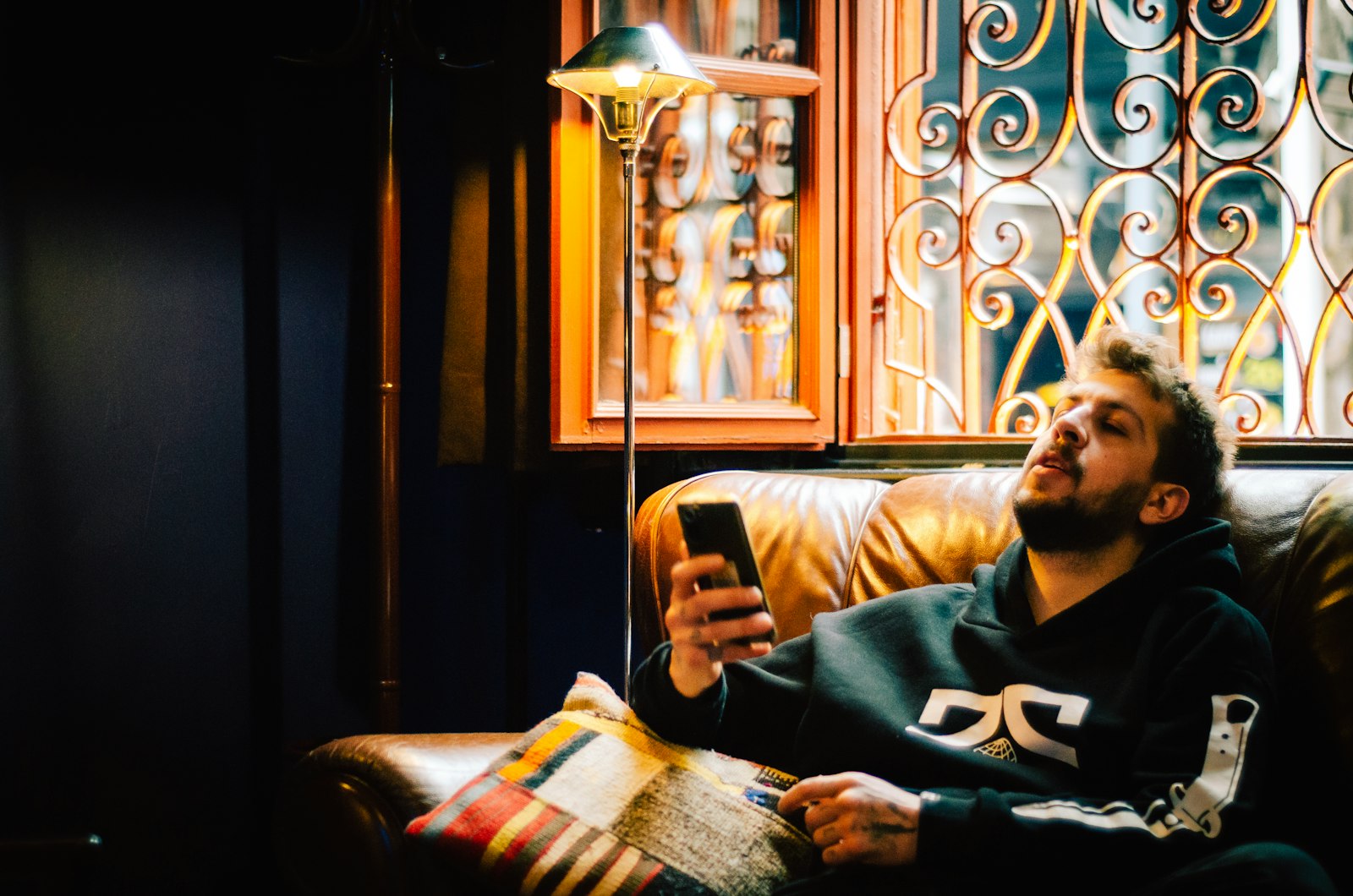 Homem sentado no sofa olhando o celular durante a noite