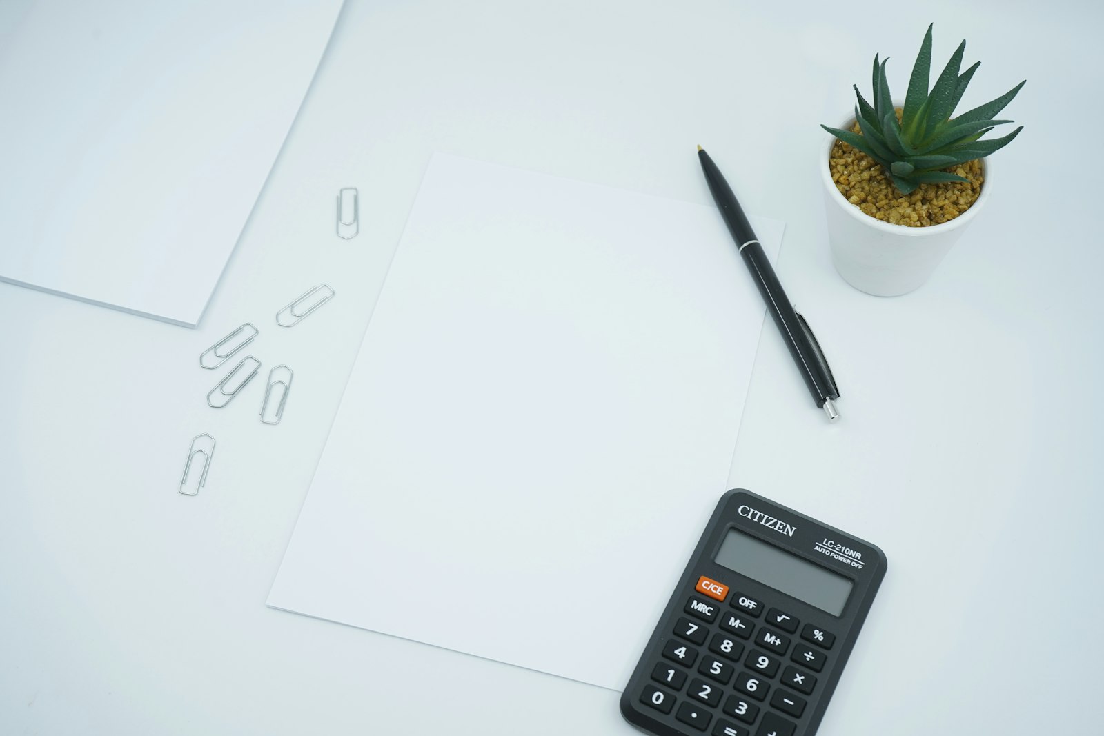 Calculadora e caneta sobre papel impresso numa mesa