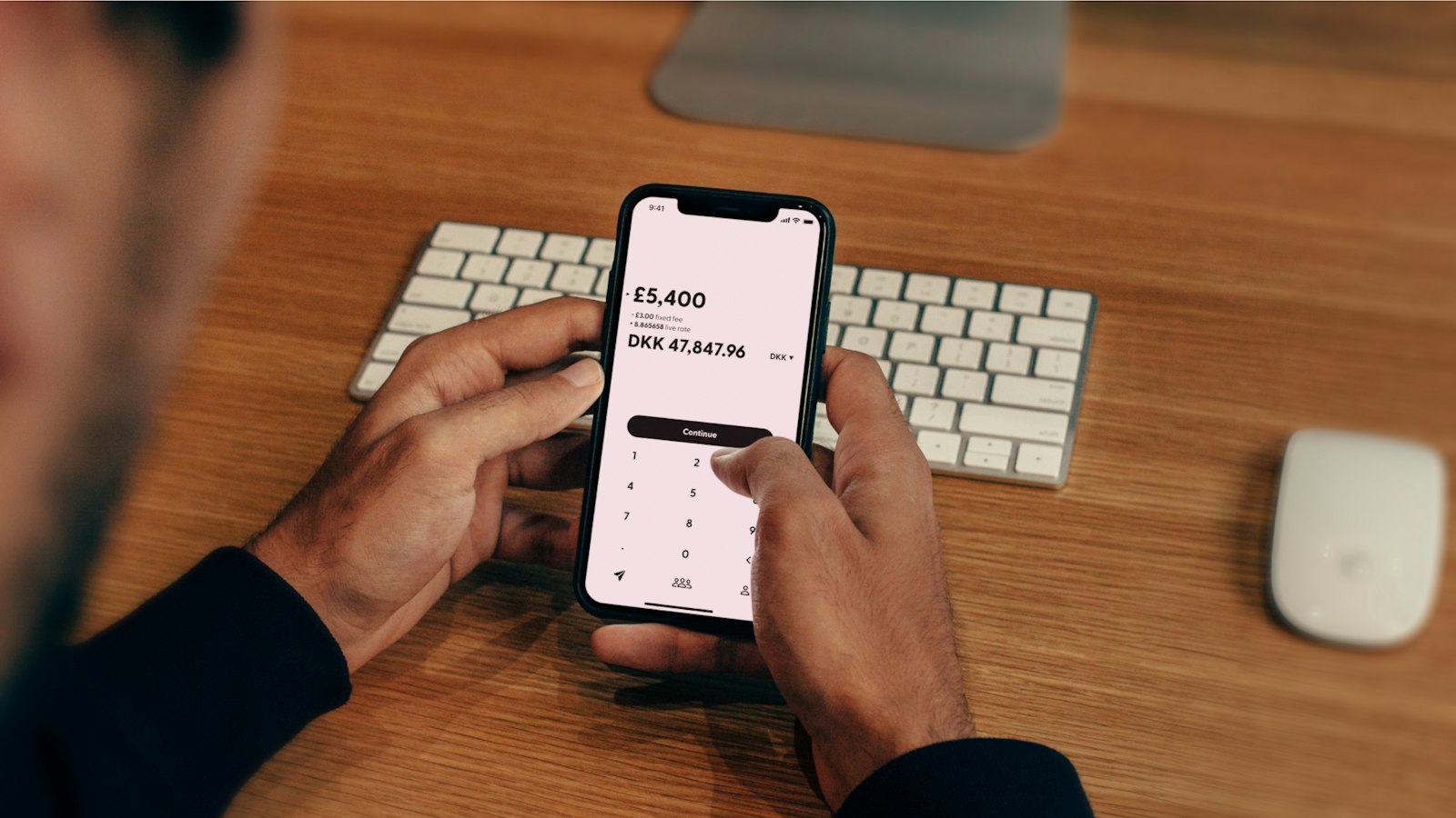 Mãos usando um aplicativo de banco no celular sobre uma mesa