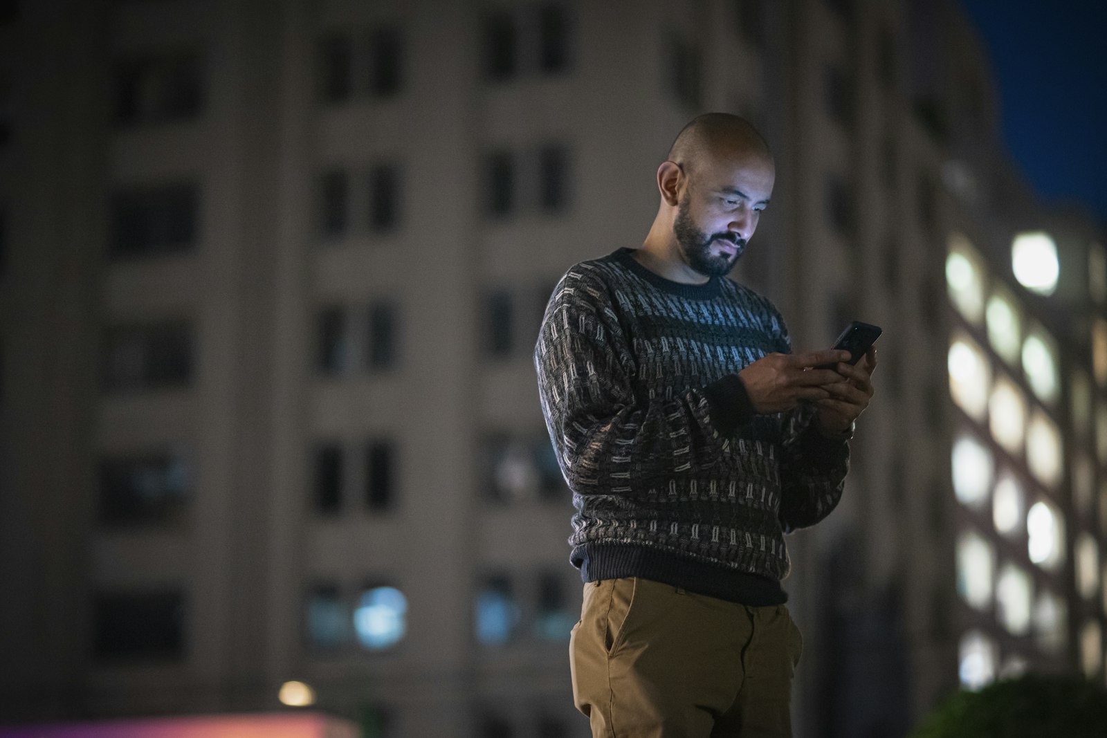 Homem de pe na calcada olhando a tela do celular