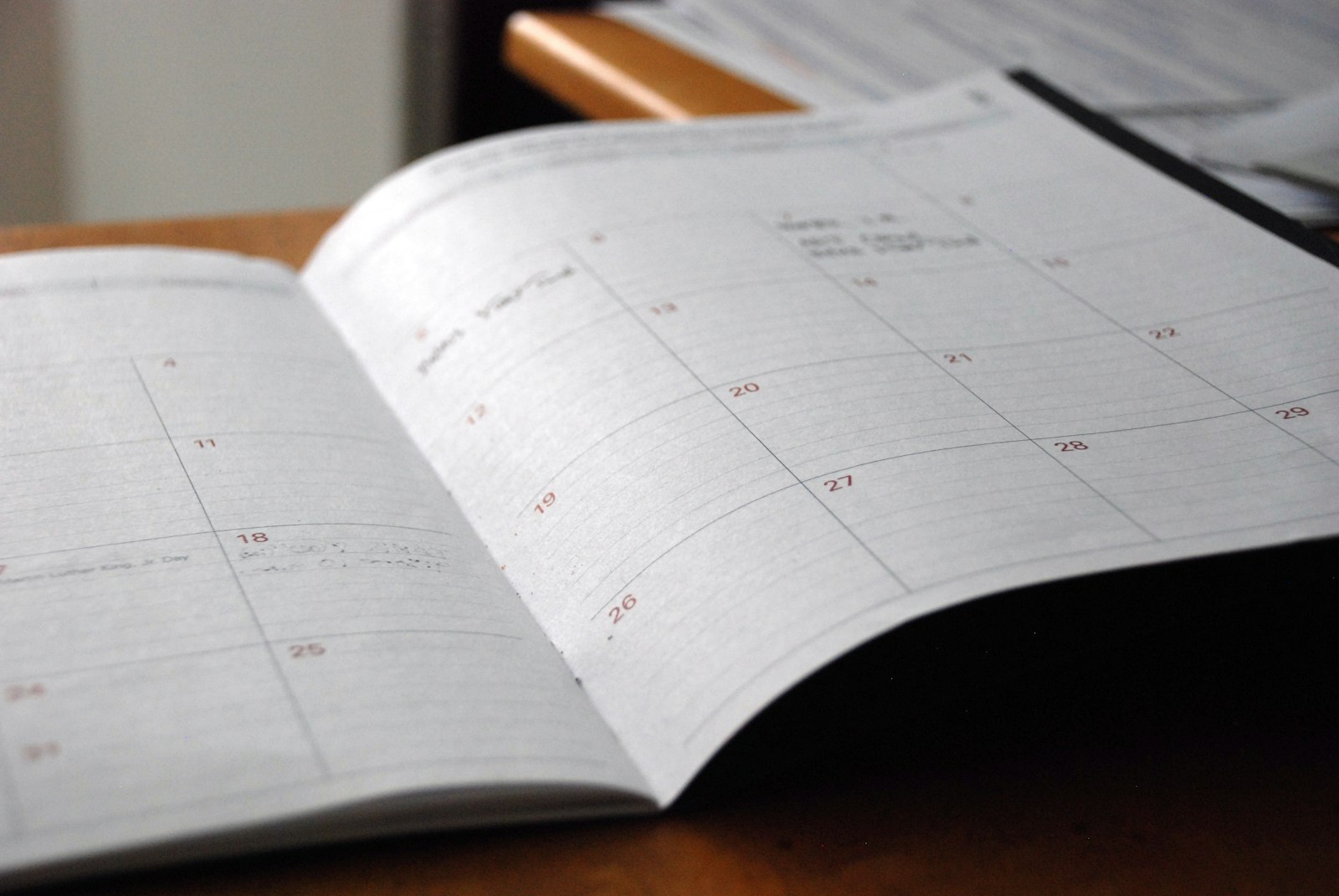Planner mensal aberto sobre uma mesa de madeira, pronto para marcar os blocos da semana