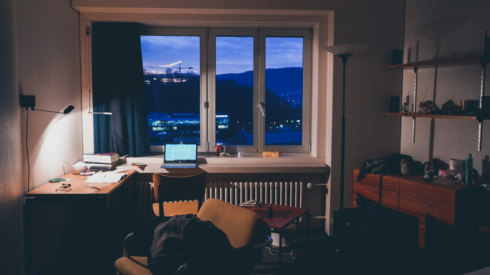 Notebook aberto sobre uma mesa de escritorio em casa a noite, com as luzes da cidade ao fundo
